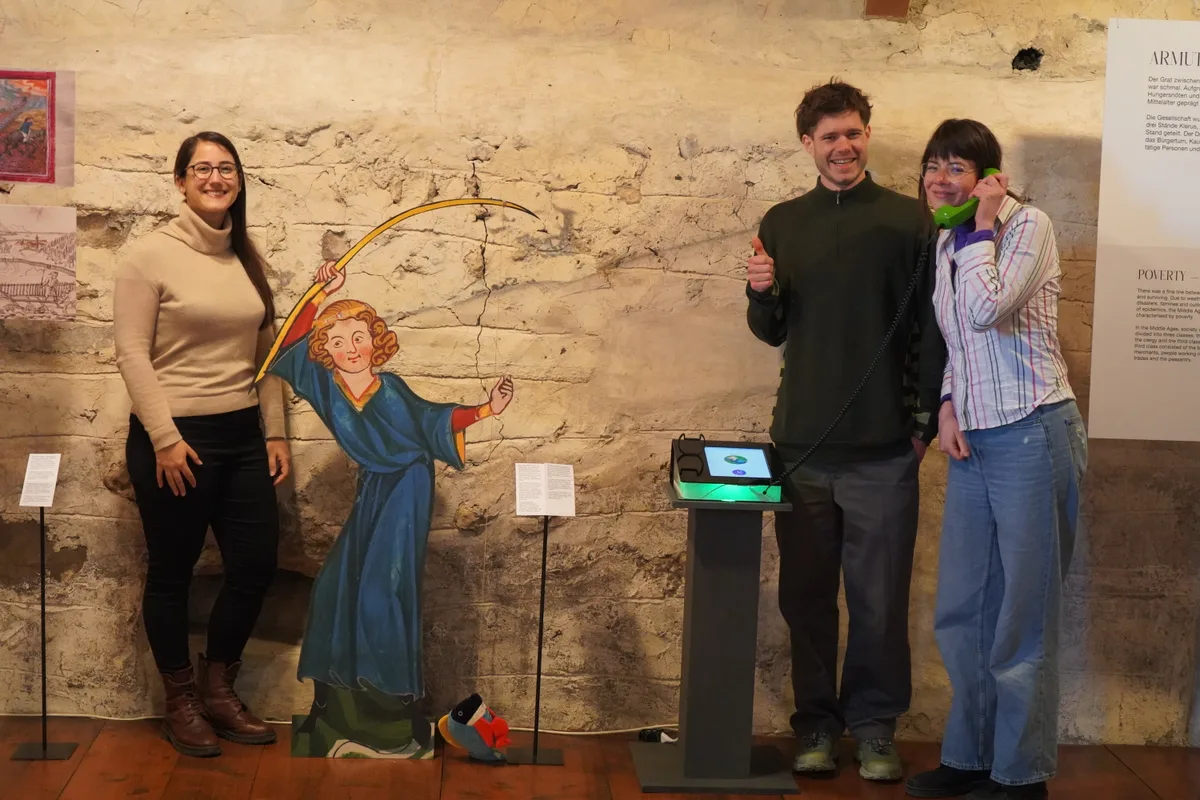 Der Chatbot und die drei Initiantinnen und Initianten im Museum.